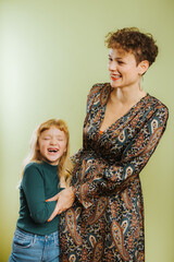 portrait of single mother and her pre-teen daughter against green background
