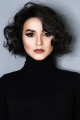 Beautiful young brunette model with bright make-up and curly hair