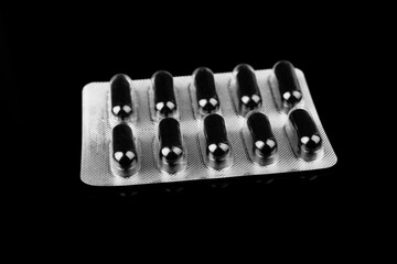 Medical capsules, pills on a black background. Copy space 