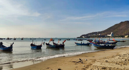Fototapeta na wymiar Fishing boats near Front Beach. Coastline of Vung Tau. Sea, palm trees and hill. Vietnam. South-East Asia 