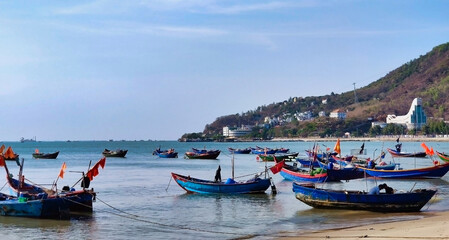 Fototapeta na wymiar Fishing boats near Front Beach. Coastline of Vung Tau. Sea, palm trees and hill. Vietnam. South-East Asia 