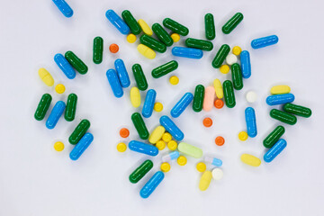 Pharmaceutical colorful pills and capsules on  white background.  A large number of tablets on the surface.
The concept of modern treatment, pharmacy, healthcare. 