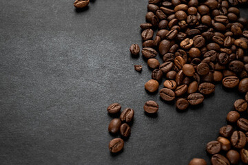 Roasted coffee beans scattered on dark background