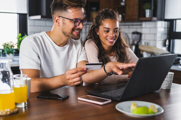Happy couple using credit card for online shopping at home