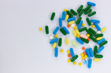 Pharmaceutical colorful pills and capsules on  white background.  A large number of tablets on the...