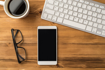 Overhead above close up view photo image of computer keyboard mug of tasty fresh morning beverage eyeglasses and digital device gadget with empty blank space for text on light brown backdrop