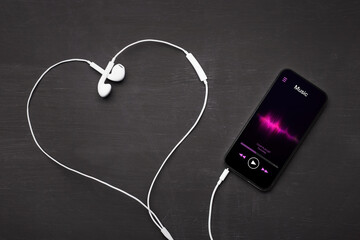 Mobile phone with music player app open and earphones shaping love heart symbol. © Kaspars Grinvalds