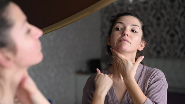 A young caucasian woman applies a cream to the skin of the neck. Morning skin care treatments. Awakening from sleep. Massage the face and neck concept. . High quality 4k footage