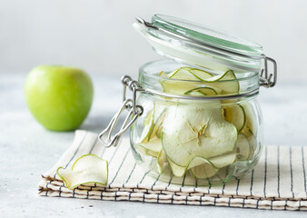 Dehydrated apple chips in glass jar on gray background. healthy vegan fruit snack. close-up.