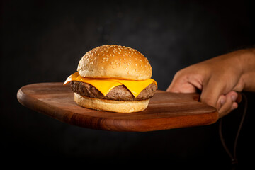 Tasty hamburger on wooden board on dark background.