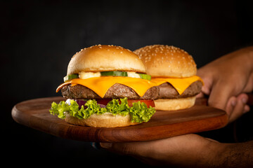 Tasty hamburgers on wooden board on dark background. - obrazy, fototapety, plakaty