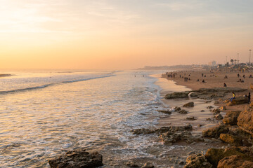 Beautiful sunset in the Atlantic ocean in Portugal and families enjoying on the beach