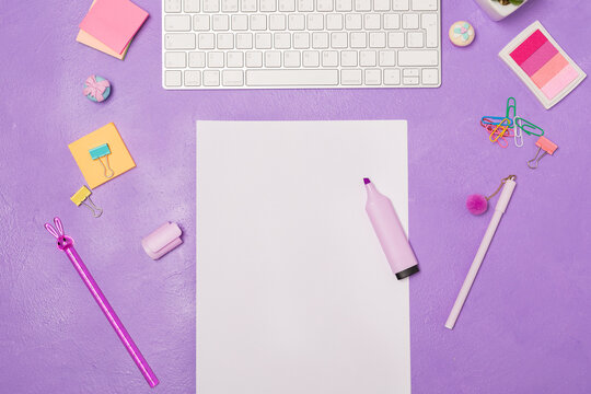Bright vivid Flat lay workspace. Blank paper list and highlighter. Stationary and keyboard on bright violet purple background, top view. Girly work desktop. Copy space. School concept. 