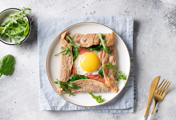 homemade buckwheat crepe galette with egg, ham and spinach on gray background. Traditional French...