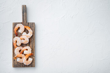Fototapeta na wymiar Whole fresh peeled cooked prawns, shrimps, on wooden cutting board, on white background, top view flat lay , with copyspace and space for text