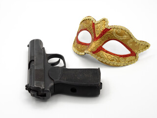 Gun, pistol, traditional golden carnival Venetian mask with red ornament on white background. Preparation for the Brazilian Festival and Mardi Gras, fat Tuesday. The concept of anonymous crime.