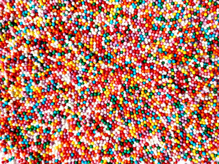 texture of multicolored sprinkles for Easter top view. different colors round small sugar balls of bright red blue and yellow colors