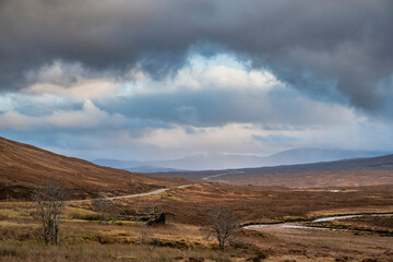 Majestic landscape image view down Glencoe Valley in Scottish Highlands with mountain ranges in dramatic Winter lighting