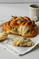 Freshly baked homemade braided brioche and cup of tea on white background.