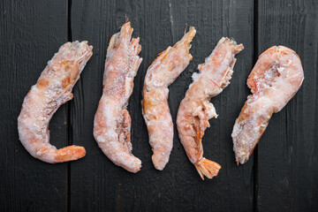 Frozen red Argentinian prawns, on black wooden table background, top view flat lay