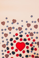 background with hearts. Blackberries, blueberries and raspberries on an orange background. A red heart surrounded by fruit. healthy eating and healthy lifestyle. Space copy text