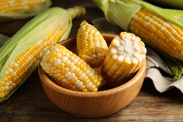 Tasty sweet corn cobs on wooden table, closeup
