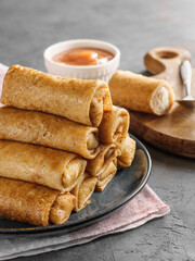 Thin crepe pancakes stuffed lie in a pyramid on the table in a rustic style. A traditional dish for the carnival.