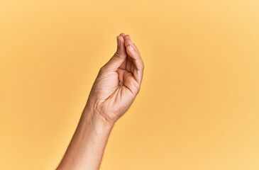 Arm and hand of caucasian man over yellow isolated background doing italian gesture with fingers together, communication gesture movement