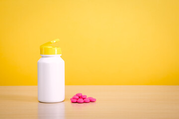 A white jar with scattered red pills on a yellow background.