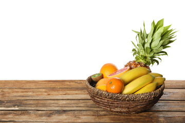 Assortment of fresh exotic fruits in basket on wooden table. Space for text