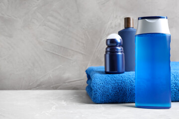 Cosmetic products and towel on light grey marble table, space for text. Men's hygiene