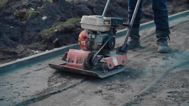 The builder levels the laid street tiles with a power tool. Construction works in the city