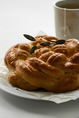 Freshly baked homemade braided brioche and cup of tea on white background.