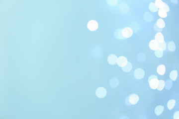 Blurred view of beautiful lights on light blue background, space for text