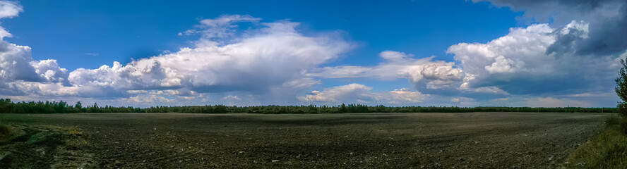 Beautiful panorama of a field over a cloudy sky in early spring