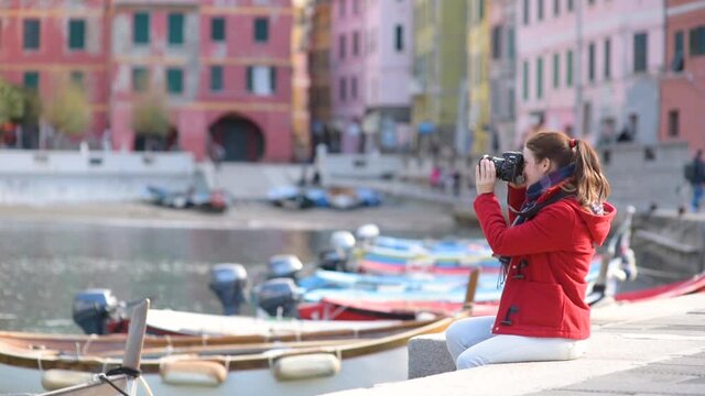 Young female tourist enjoying the view of Vernazza, one of the five centuries-old villages of Cinque Terre, located on rugged northwest coast of Italian Riviera, Liguria, Italy. Traveling off season.