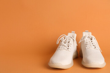 Pair of stylish sport shoes on orange background. Space for text