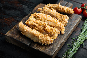 Crispy chicken tenders on dark wooden background