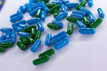 Green and blu capsules on white background. The concept of modern treatment, pharmacy, healthcare. 