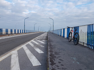 Widok nieczynnego wiaduktu nad rzeką Wisła, na którym widać jezdnie oraz stojący na chodniku rower.
