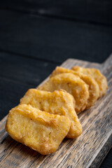 Nuggets on black wooden background, with space for text