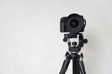 The camera standing on a tripod against the background of the wall in the room. The camera is...
