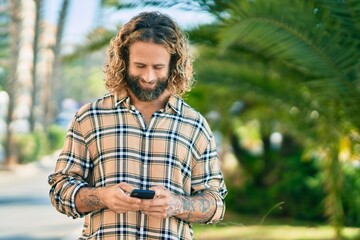 Young caucasian man smiling happy using smartphone at the park.