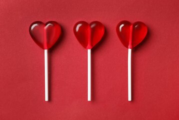 Sweet heart shaped lollipops on red background, flat lay. Valentine's day celebration