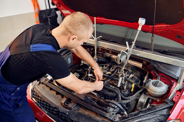 Repairing a car engine in auto-service center. Auto mechanic working in the garage