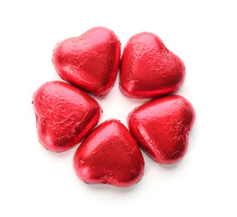 Heart shaped chocolate candies in red foil on white background, top view