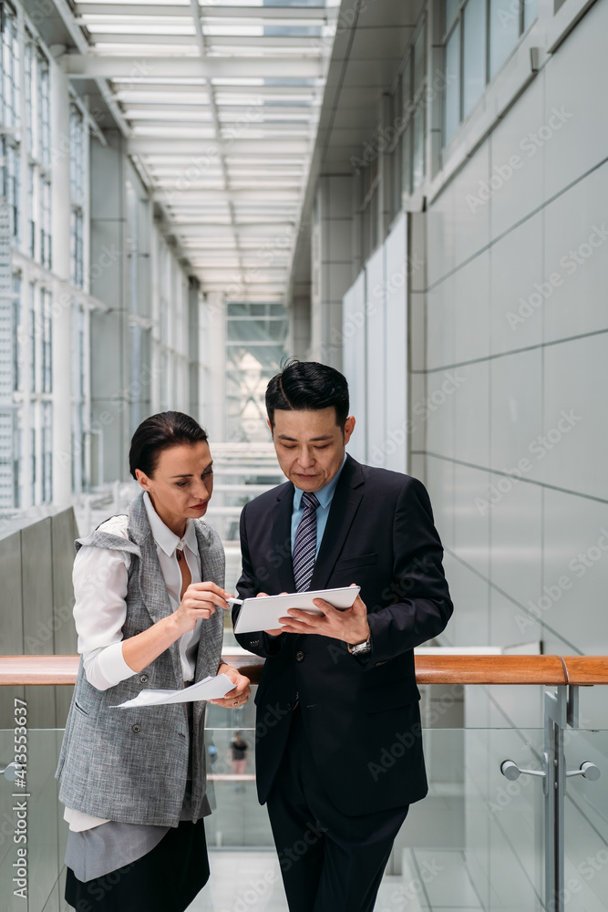 Wall mural business people using digital tablet together. handsome businessman showing tablet to his female col