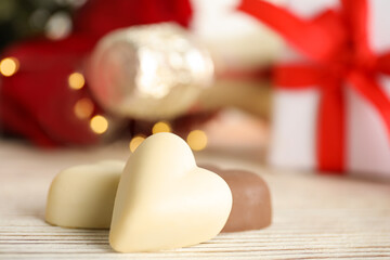 Tasty heart shaped chocolate candies on white wooden table, closeup. Valentine's day celebration