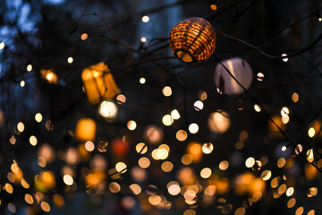 Colorful lampions and lanterns up a tree at night in the garden. A wedding, event or festival...