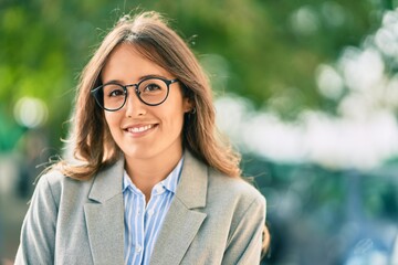 Obraz premium Young hispanic businesswoman smiling happy standing at the city.